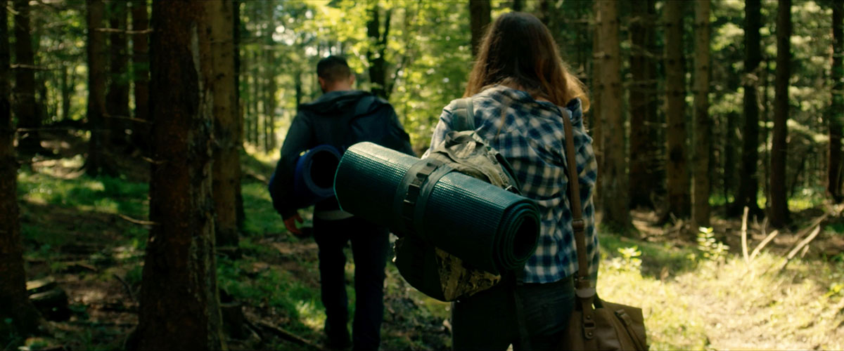 People carrying luggage through the wood.